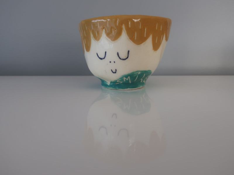 Tasse ocre au visage paisible
